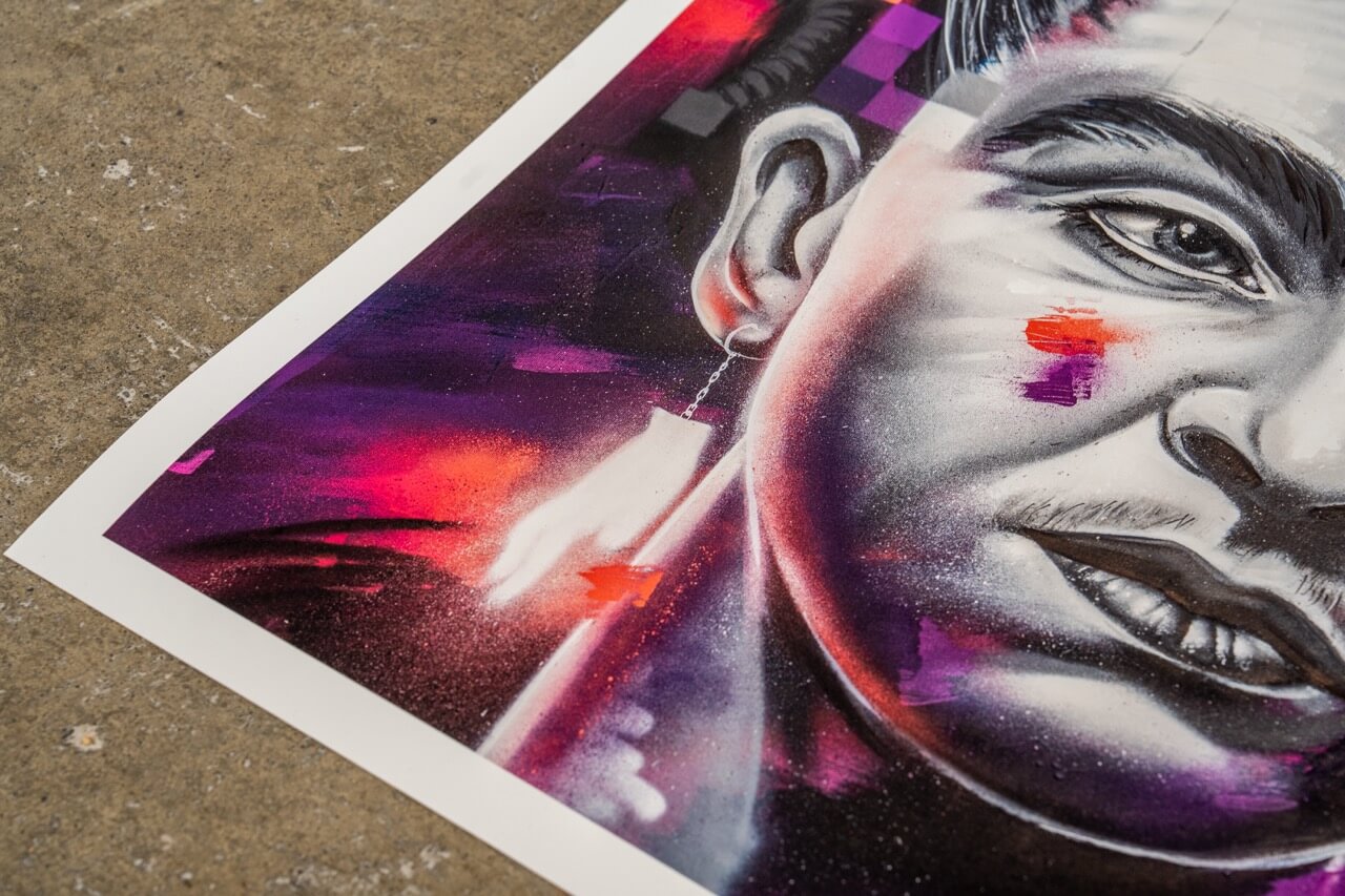Detailaufnahme eines Graffiti-Art-Prints von Stone Graffiti. Das Kunstwerk zeigt ein hyperrealistisches Porträt mit intensiven Schattierungen in Schwarz-Weiß, ergänzt durch abstrakte, leuchtende Akzente in Lila, Rot und Orange. Besonders auffällig ist das künstlerisch interpretierte Ohr mit einem filigranen Kettenohrring sowie geometrischen und gesprühten Farbdetails. Die Mischung aus realistischer Malerei und Street-Art-Elementen verleiht dem Bild eine moderne, dynamische Ästhetik.