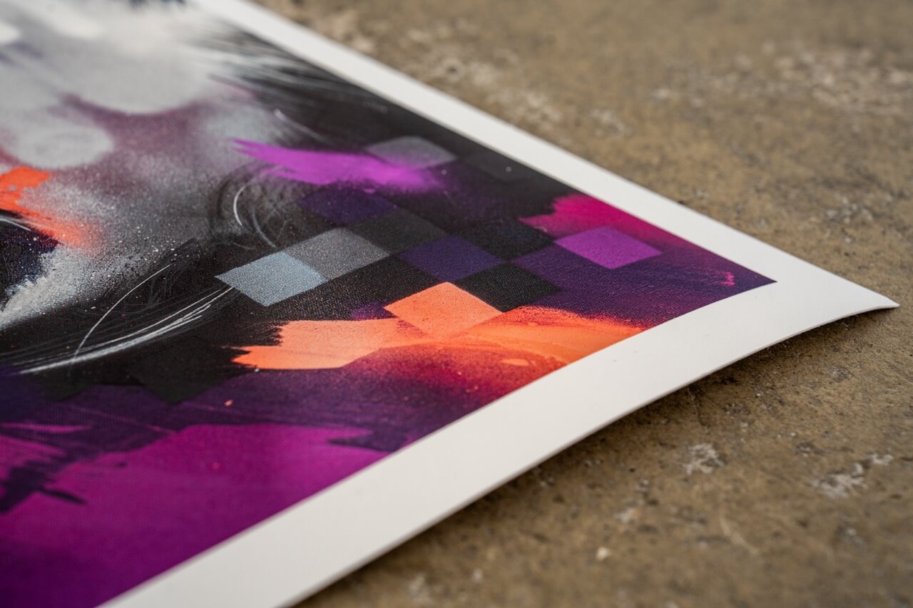 Detailaufnahme der unteren Ecke eines hochwertigen Graffiti-Art-Prints von Stone Graffiti. Sichtbar sind abstrakte, geometrische Muster in Lila, Schwarz und Grautönen, ergänzt durch kräftige Pinselstriche in Orange und Magenta. Der Druck hebt sich durch seine leuchtenden Farben und feinen Details ab, während die leicht gewölbte Papierkante die hochwertige Druckqualität betont. Die Betonoberfläche im Hintergrund verstärkt den urbanen Street-Art-Charakter des Kunstwerks.