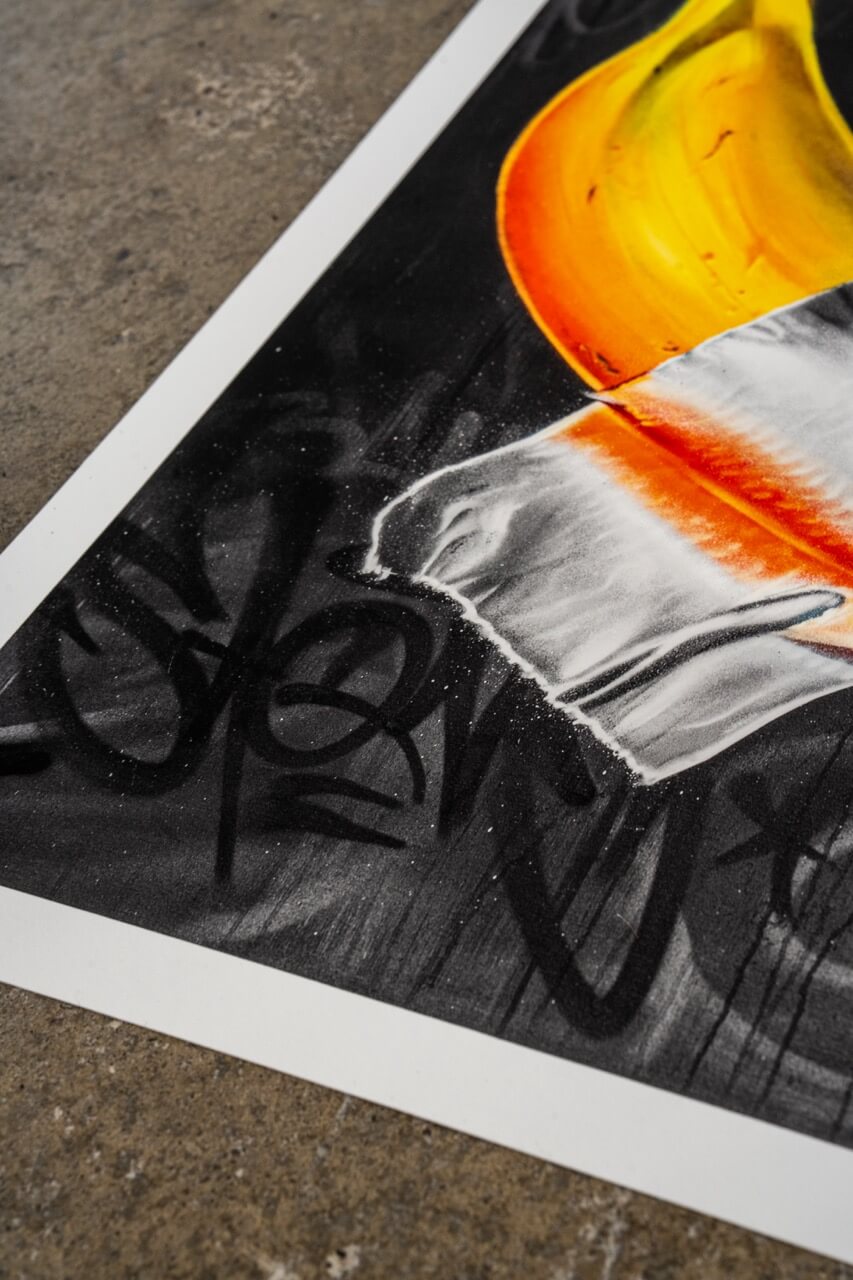 Detailaufnahme eines Graffiti-Kunstdrucks von Stone Graffiti. Das Kunstwerk zeigt eine lebendig gemalte Banane mit silbernem Klebeband auf einem dunklen Hintergrund. Der untere Rand des Bildes ist mit gesprühten Graffiti-Tags versehen, die dem Werk eine rohe, urbane Ästhetik verleihen. Der hochwertige Druck liegt auf einer Betonoberfläche, wodurch die Street-Art-Anmutung verstärkt wird.