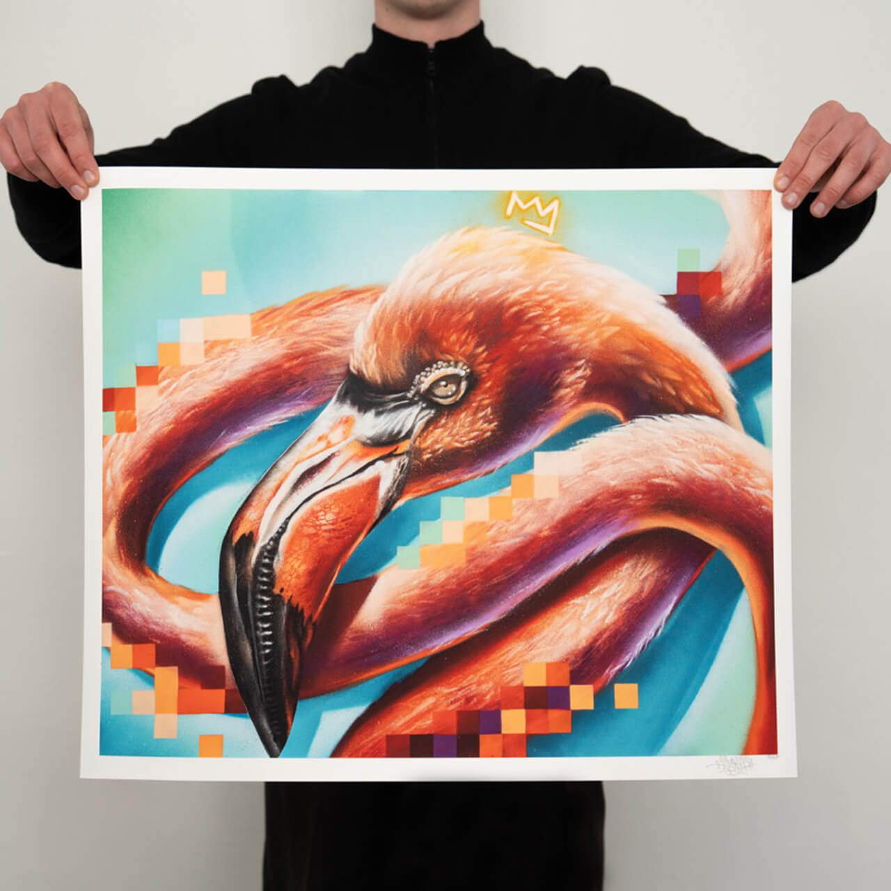 Person in schwarzer Kleidung hält einen hochwertigen Graffiti-Kunstdruck von Stone Graffiti vor einer weißen Wand. Das Kunstwerk zeigt einen farbenprächtigen Flamingo mit realistischen Details in Orange- und Rottönen, kombiniert mit abstrakten, pixelartigen Farbverläufen in Blau und Rot. Über dem Kopf des Flamingos ist eine kleine Krone als ikonisches Graffiti-Element zu sehen.