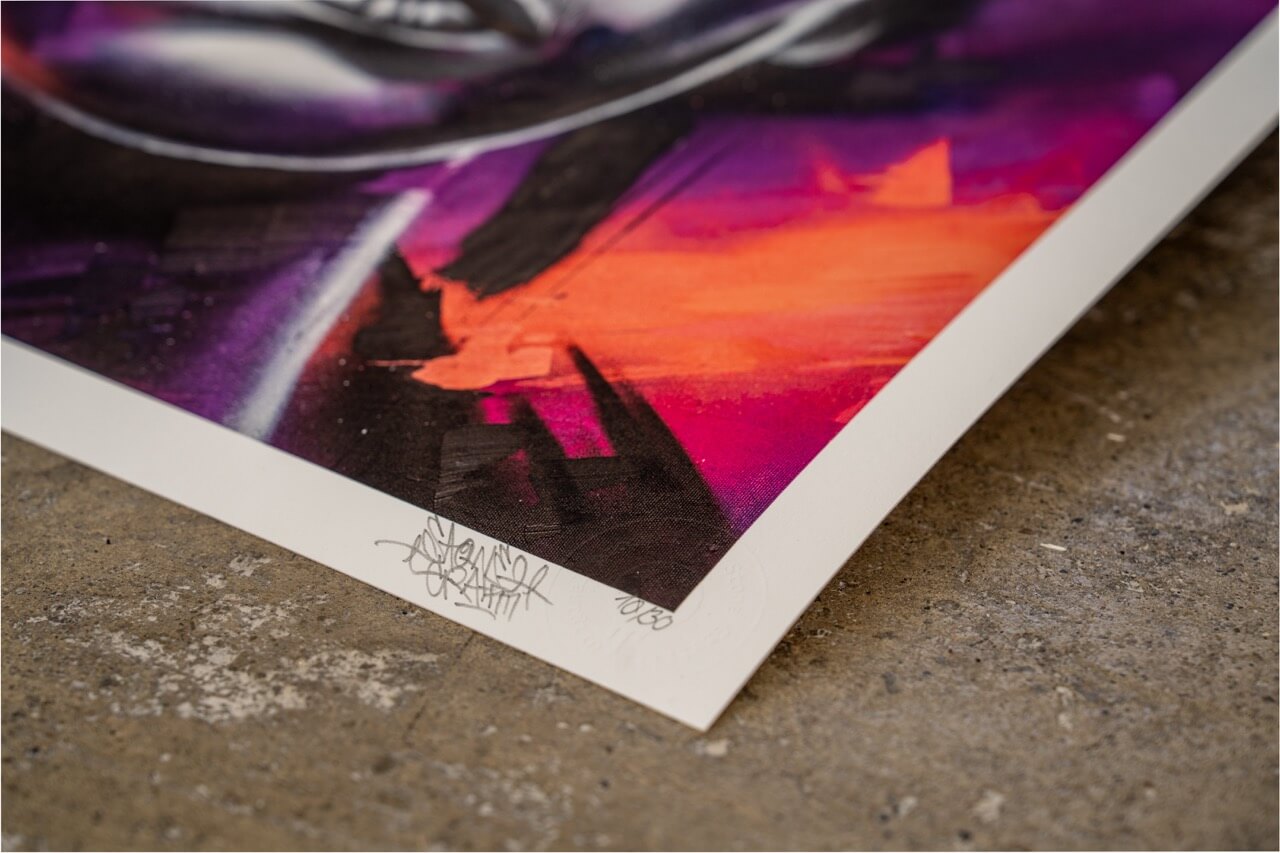Detailaufnahme eines hochwertigen Graffiti-Kunstdrucks von Stone Graffiti. Der Rand des Prints zeigt eine feine Künstler-Signatur und eine Prägung als Echtheitszertifikat. Die lebhaften Farben in Lila, Orange und Schwarz erzeugen einen dynamischen, urbanen Look. Das Bild liegt auf einer rauen Betonoberfläche, die den Street-Art-Charakter unterstreicht.