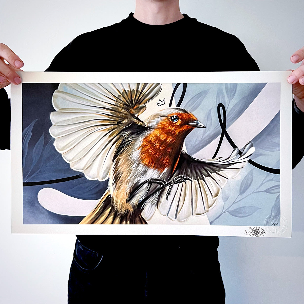 Das Bild zeigt eine Person, die einen hochwertigen Kunstdruck mit einem Rotkehlchen in dynamischer Flugpose präsentiert. Die Kombination aus realistischer Darstellung und abstrakten Formen im Hintergrund verleiht dem Werk eine moderne und zugleich natürliche Ästhetik.