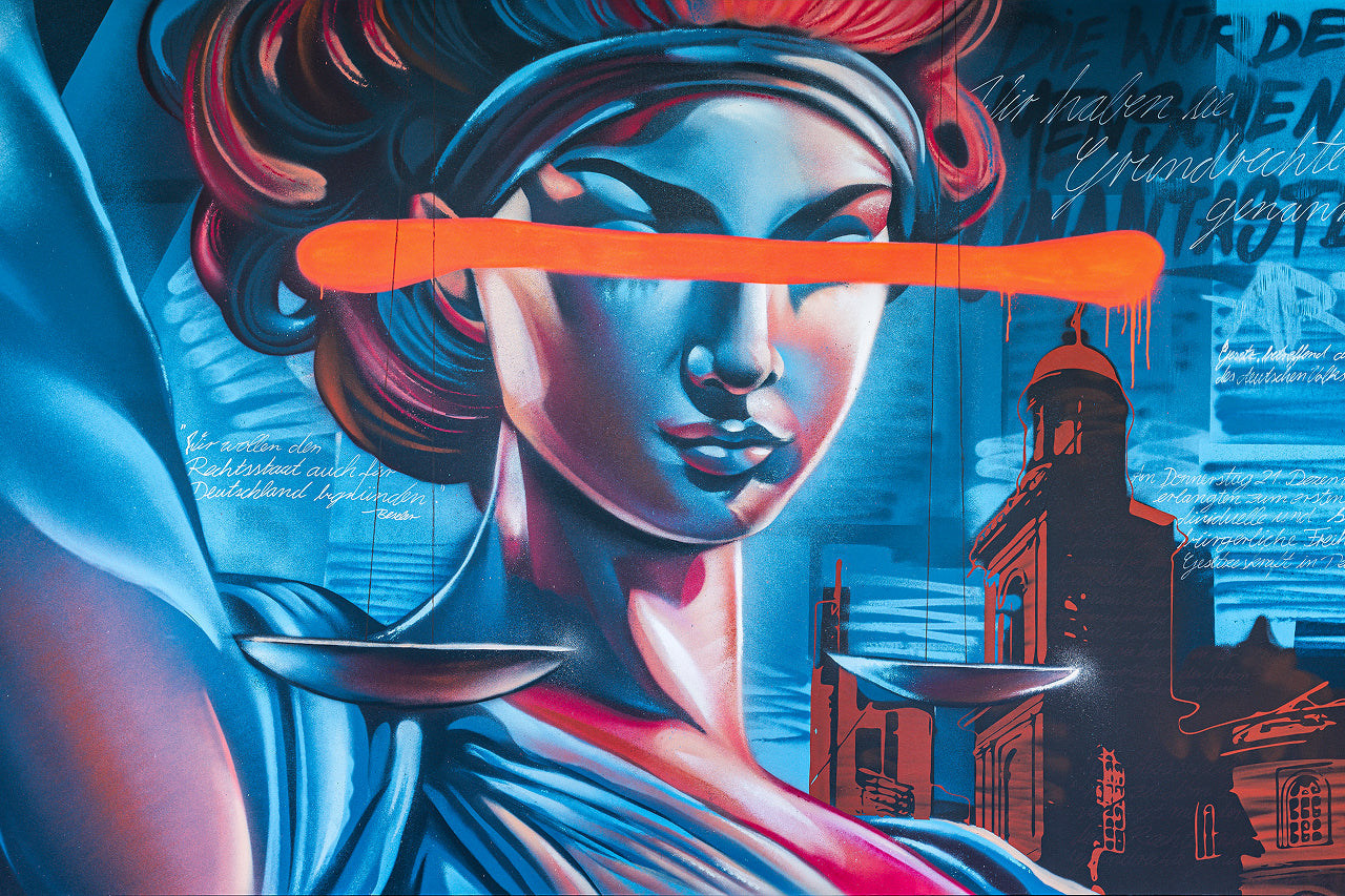 Die klassische Justitia-Figur mit der Augenbinde wird hier modern interpretiert – die leuchtend orange Balken über den Augen wirken wie eine Zensur oder Mahnung. Die Waage bleibt zentral, Symbol für Ausgewogenheit und Verantwortung. Begleitet von Zitaten zur Bedeutung des Rechtsstaats erinnert das Werk daran, dass Freiheit und Gerechtigkeit keine Selbstverständlichkeit sind – sondern verteidigt werden müssen.
