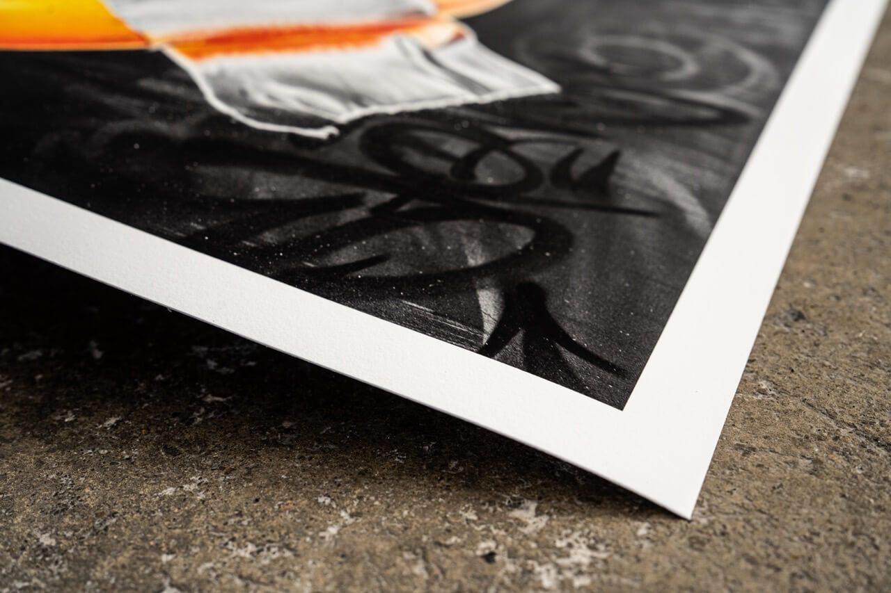 Nahaufnahme des unteren Rands eines hochwertigen Graffiti-Art-Prints von Stone Graffiti. Der Print zeigt einen dunklen Hintergrund mit gesprühten Graffiti-Tags, während der Rand des Papiers sich leicht vom rauen Betonboden abhebt. Die feine Struktur des Drucks sowie die intensive Farbtiefe sind sichtbar und unterstreichen die hohe Qualität des Kunstdrucks.