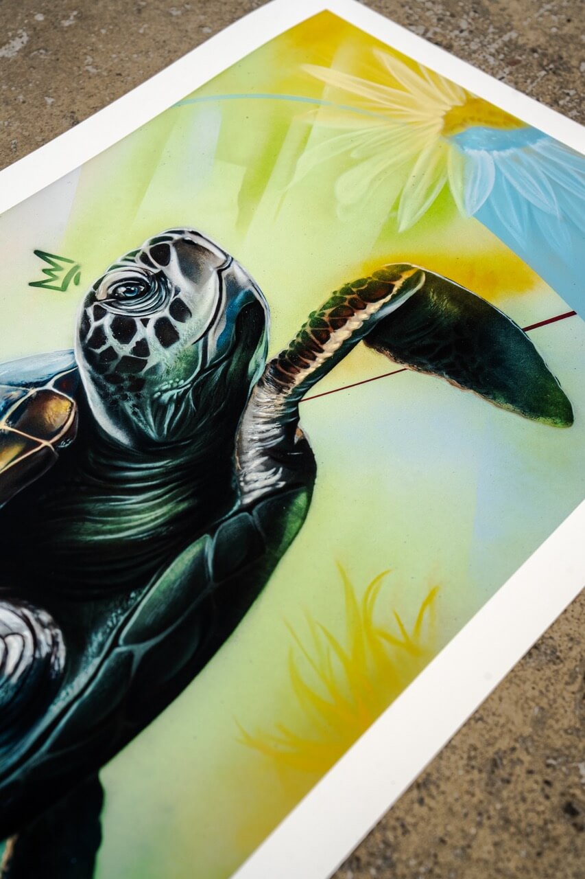 Detailaufnahme eines Kunstdrucks von Stone Graffiti mit einer hyperrealistischen Meeresschildkröte. Der Druck besticht durch gestochen scharfe Details der Schildkröte, insbesondere die Maserung der Haut und die Lichtreflexe auf dem Panzer. Die stilisierte Krone über ihrem Kopf dient als Markenzeichen des Künstlers. Der Hintergrund zeigt einen sanften Farbverlauf aus Gelb, Grün und Blau mit abstrakten grafischen Elementen und einer angedeuteten Blüte in der oberen rechten Ecke.