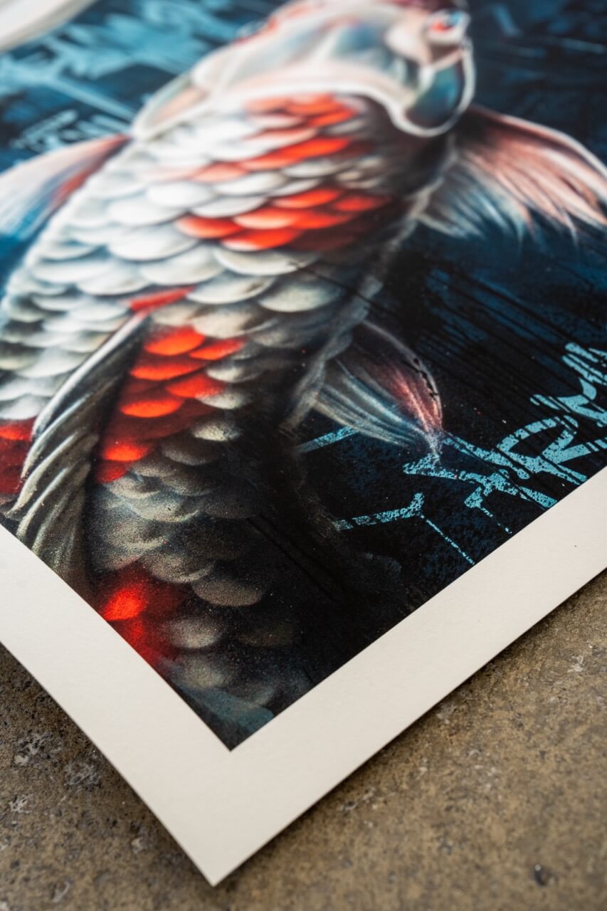 Die Nahaufnahme hebt die schimmernden Schuppen des Koi-Fisches hervor, die in einem harmonischen Farbverlauf aus Weiß, Silber und leuchtendem Rot gestaltet sind. Die fein nuancierte Airbrush-Technik sorgt für eine realistische Textur und verleiht dem Fisch eine dynamische, fast dreidimensionale Wirkung. Der dunkle, mit Graffiti-Elementen versehene Hintergrund verstärkt den Kontrast und bringt die detailreichen Highlights des Kunstwerks besonders zur Geltung.