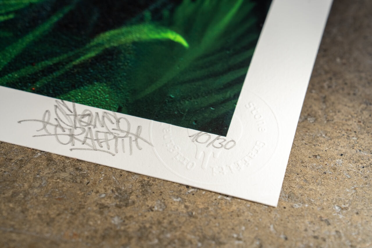 Der untere linke Rand des Kunstwerks zeigt eine handschriftliche Signatur mit dem Schriftzug "STONE GRAFFITI", begleitet von einer geprägten Prägung mit den Worten "Stone Graffiti" und "Certified Original". Daneben ist die Limitierungsnummer "10/30" vermerkt. Das Kunstwerk selbst weist intensive Grüntöne mit detailreichen Strukturen auf, die an Blätter oder tropische Pflanzen erinnern. Die Textur des Prints ist leicht erkennbar, mit feinen Farbverläufen und subtilen Lichteffekten.