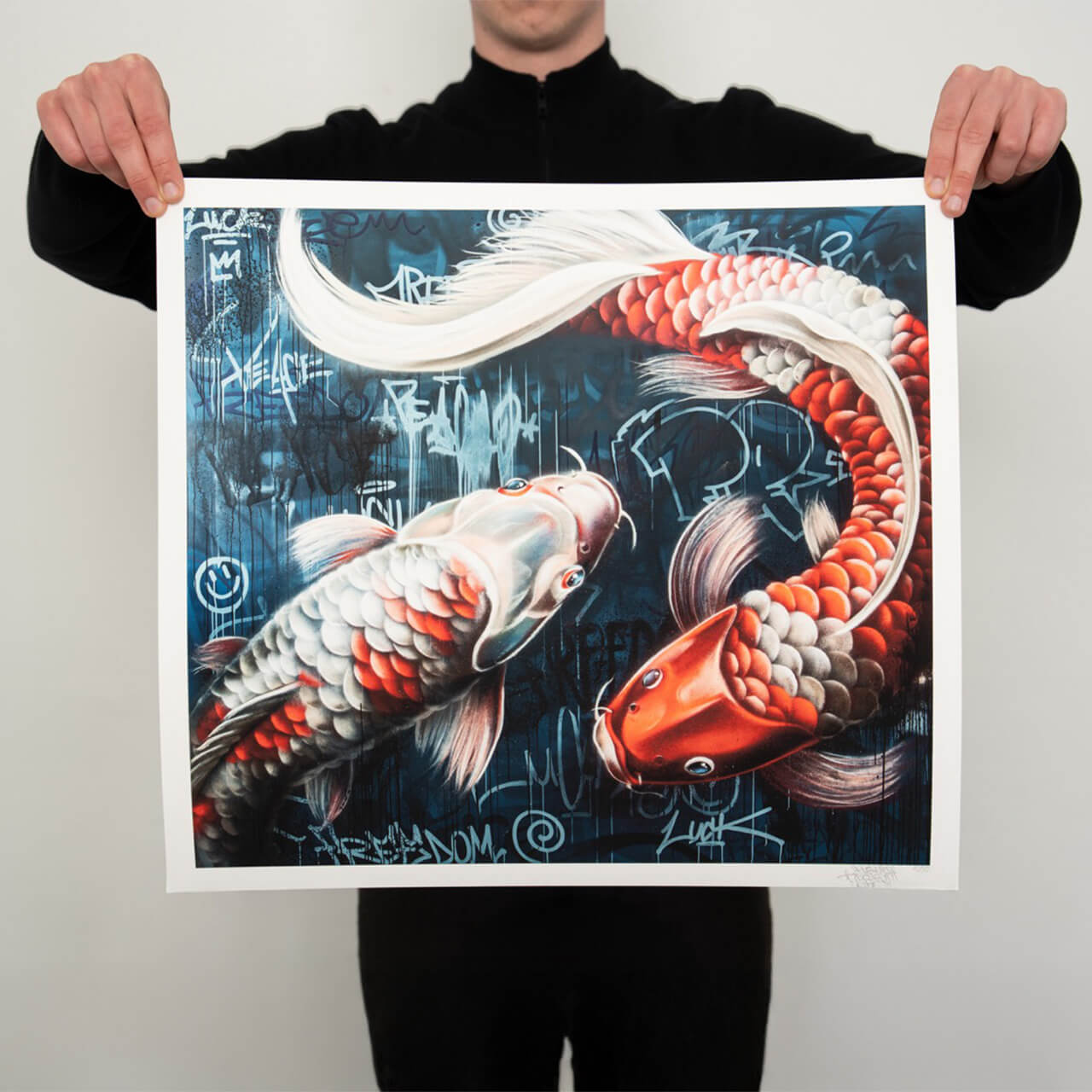 Ein hochwertiger Kunstdruck von Stone Graffiti mit zwei detailliert ausgearbeiteten Koi-Fischen in lebendigen Rot- und Weißtönen. Die Fische schwimmen in einer kreisförmigen Bewegung vor einem tiefblauen, urbanen Hintergrund, der mit Graffiti-Elementen und Tags versehen ist. Die dynamische Komposition vermittelt das Gefühl von Bewegung und Harmonie, während die feine Schattierung und Textur die Schuppen der Koi realistisch hervorheben.