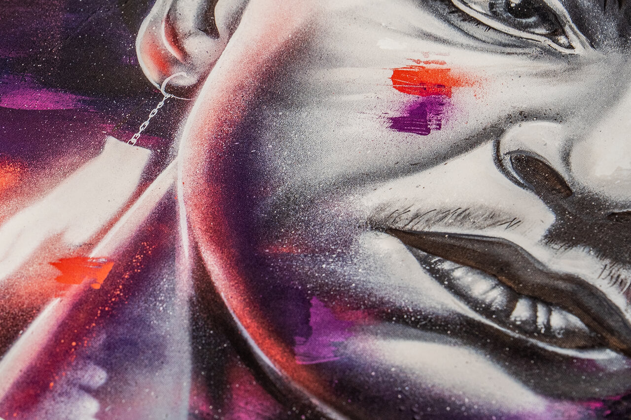 Ein Nahaufnahmeausschnitt eines Street-Art-Porträts zeigt den unteren Bereich des Gesichts mit detailreichen Schattierungen und Farbakzenten. Der Fokus liegt auf der markanten Lippenpartie, einem filigranen Ohrring und dynamischen Pinselstrichen in Rot und Lila, die das Bild lebendig wirken lassen.