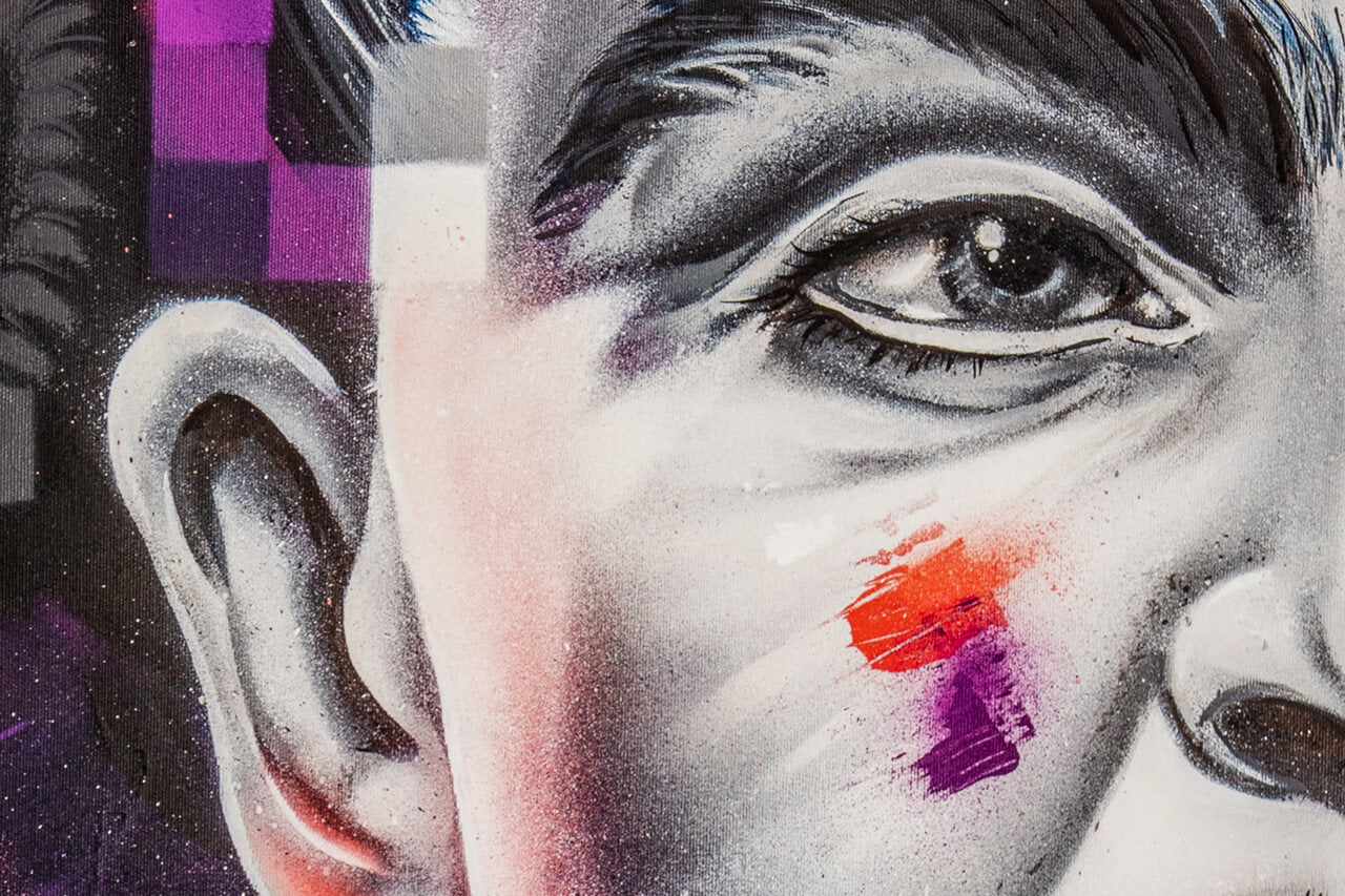 Nahaufnahme eines Street-Art-Porträts mit Fokus auf das Auge und die Gesichtszüge. Feine Schattierungen und kräftige Pinselstriche in Rot und Lila setzen lebendige Akzente, während verpixelte Muster das Bild modern und dynamisch wirken lassen.