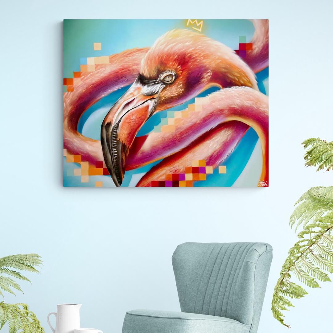 Dieses Bild zeigt ein Wandbild oder Leinwanddruck mit einem stilisierten Flamingo in leuchtenden Farben – vorwiegend Rosa, Orange, Türkis und Blau. Pixelartige Farbflächen ergänzen das Motiv und verleihen dem Werk einen digitalen, modernen Touch. Oberhalb des Flamingos ist eine kleine, gelbe Krone zu sehen – ein wiederkehrendes Symbol in der Bildwelt von Street-Art-Künstler:innen. Die Szene spielt sich in einem minimalistischen, modernen Wohnraum ab, der mit einer hellblauen Wand.